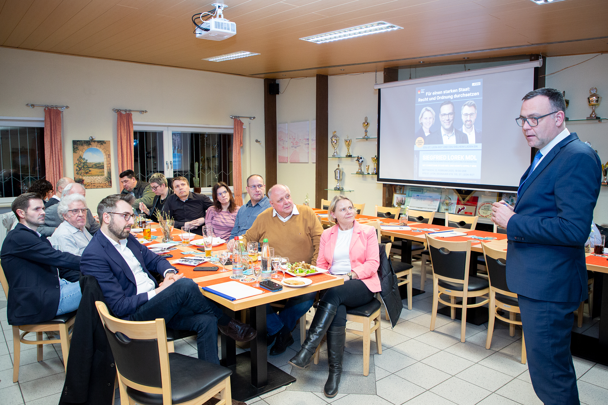 LOREK-12Feb2025-Pressefoto-Busse Auf dem Foto: Klartext sprach Siegfried Lorek (stehend) in St. Leon-Rot. Am Tisch vorne: Christiane Staab MdL, ihr gegenüber Moritz Oppelt MdB.